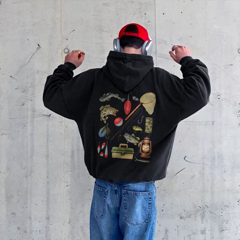 Man wearing a cozy dark gray fishing hoodie featuring a funny dad joke and fish graphic outdoors near a lake