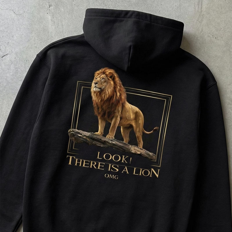 Black hoodie featuring a realistic graphic of a lion standing on a log framed in gold with text reading LOOK THERE IS A LION OMG